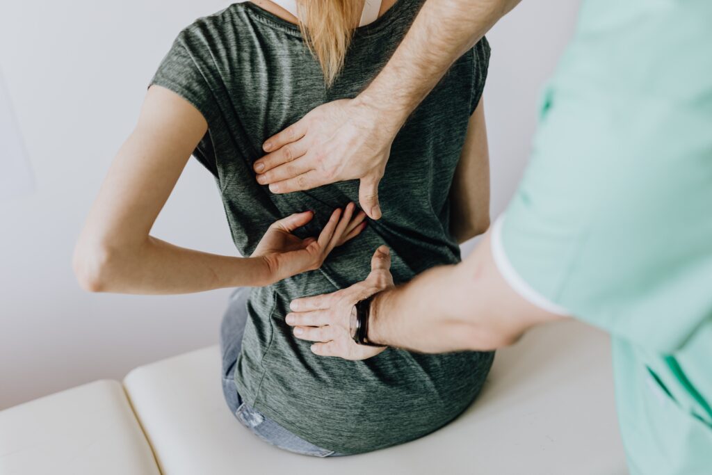 Frau mit Rücken- und Nackenbeschwerden lässt sich beim Physiotherapeuten behandeln.
